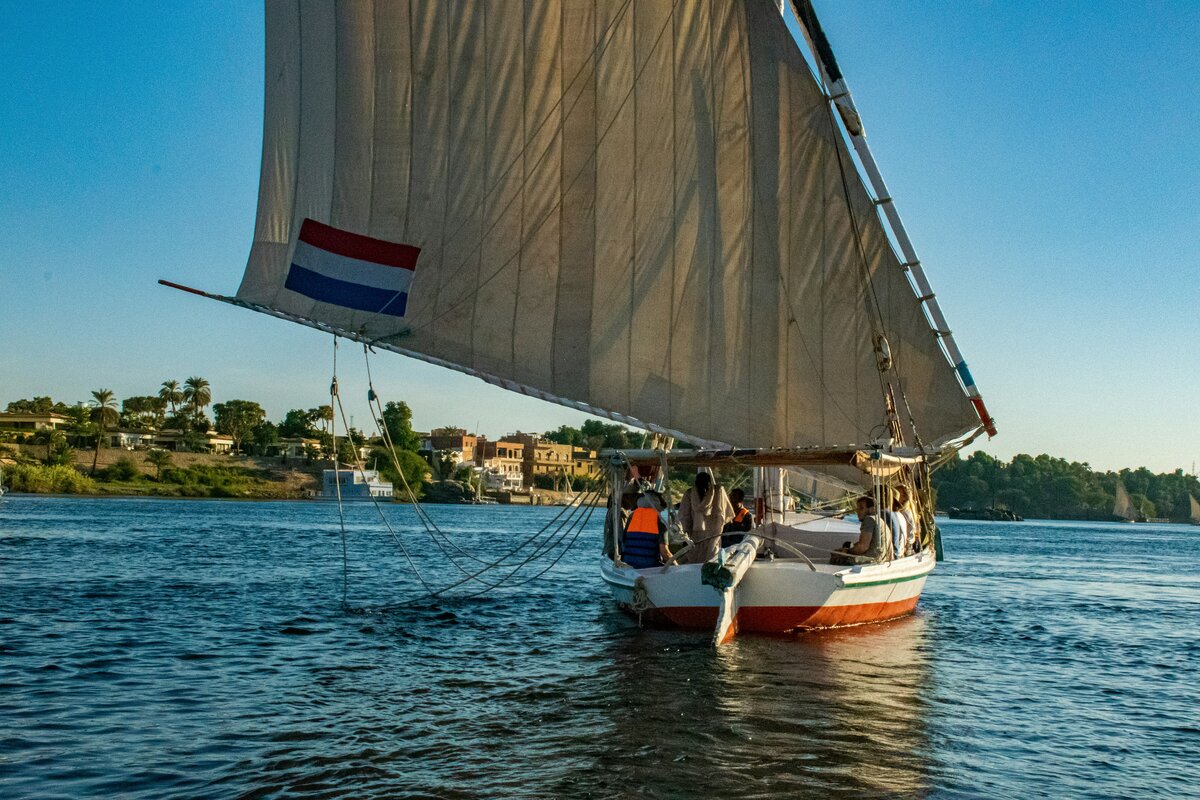 Luxury Nile cruise ship sailing near Aswan temples at sunset